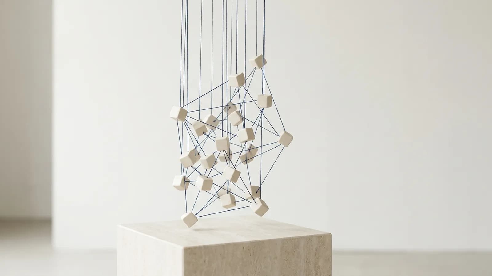 Small pale cubes joined by fine indigo threads forming a network