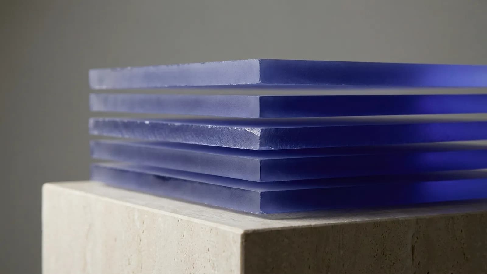 Frosted acrylic sheets stacked with gaps, edges catching indigo light