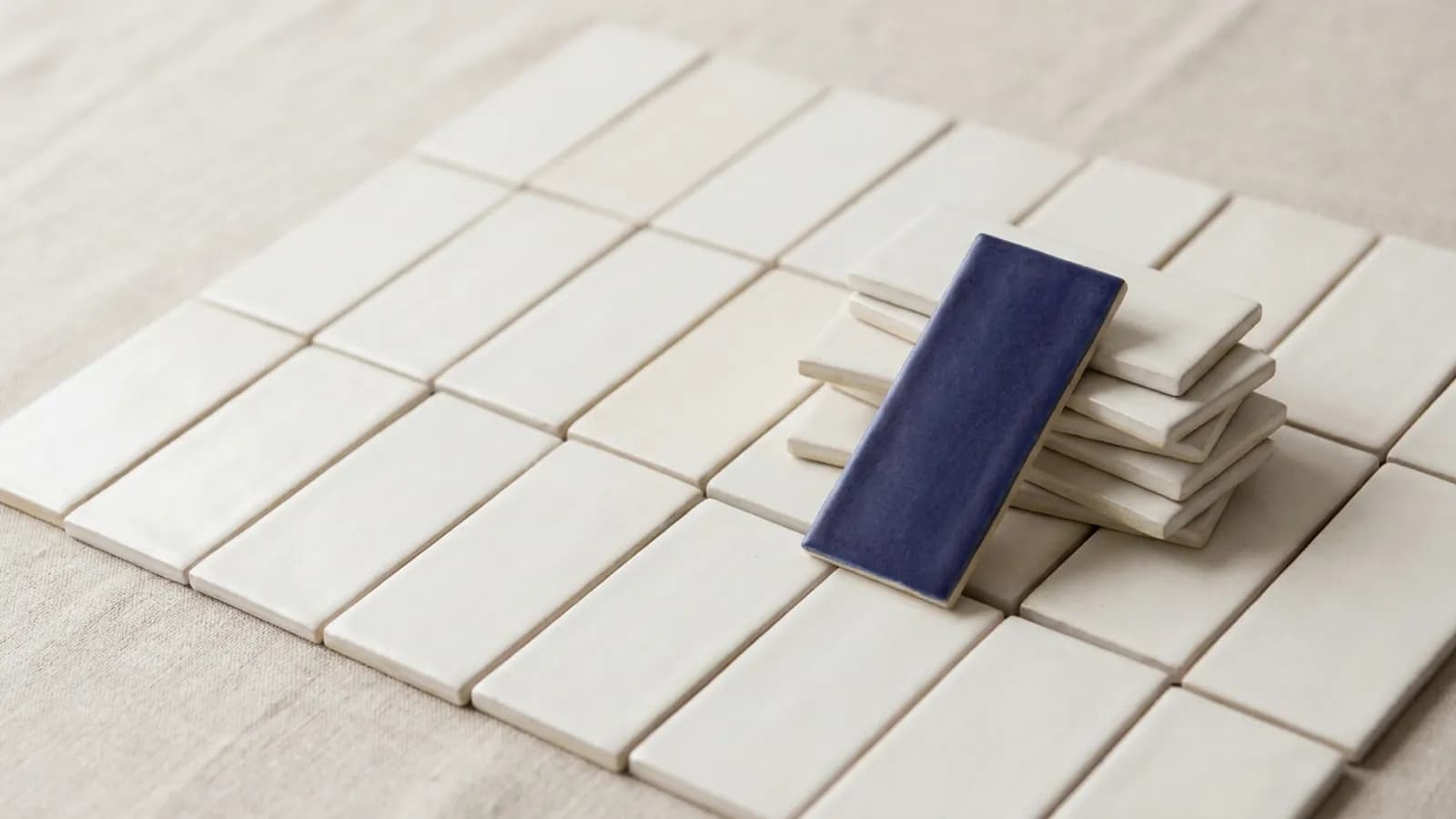 A grid of blank ceramic tiles with a few lifted and stacked aside