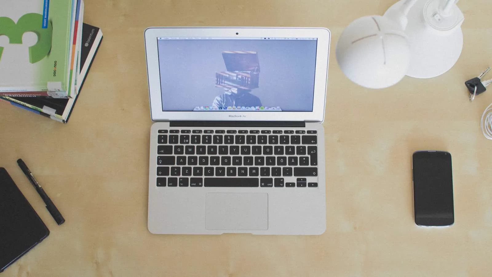 Overhead view of a laptop, phone, headphones and magazines on a yellow desk
