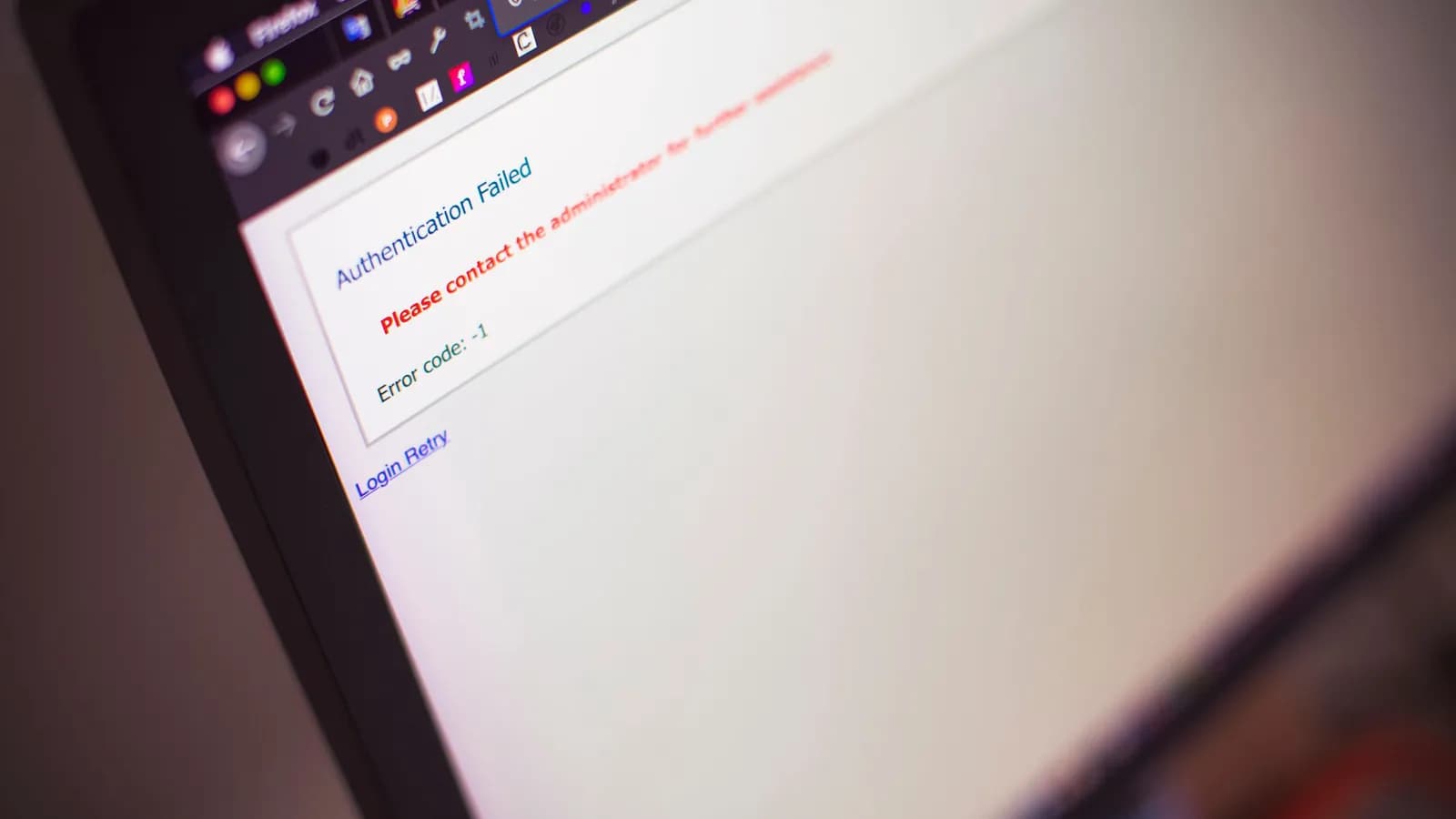 Photograph: a laptop screen at an angle showing a browser page reading Authentication Failed, with a Login Retry link beneath it