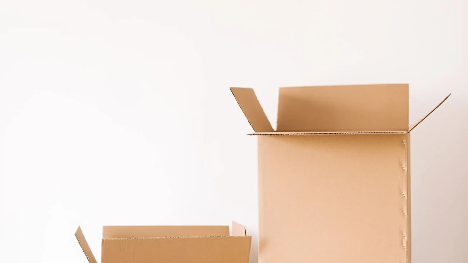 Two open cardboard boxes on a pale surface against a plain white wall