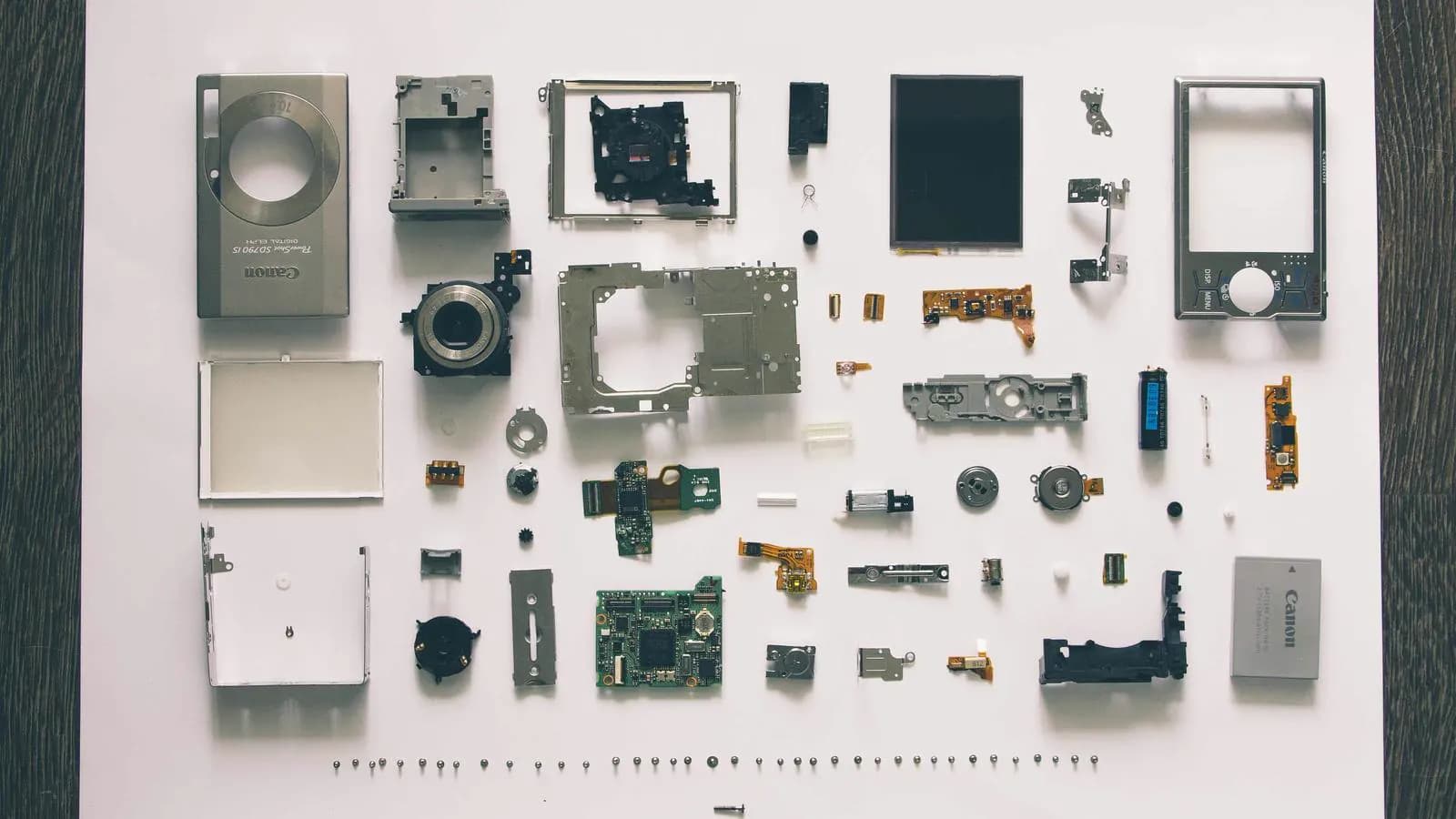 Disassembled camera parts laid out in neat rows on a white surface