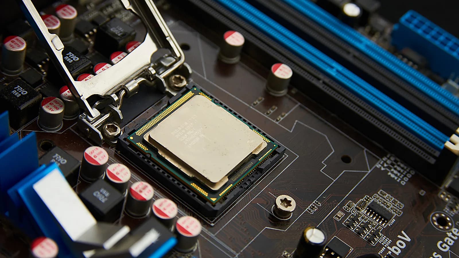 Photograph: a processor seated in an open motherboard socket with the retention arm raised, blue memory slots running along the top